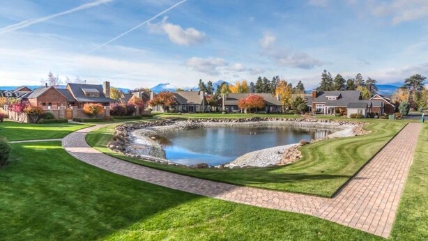 Un quartier résidentiel avec un étang, des maisons et une pelouse bien entretenue.