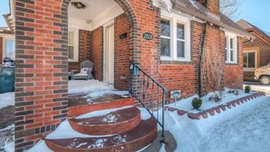 Une maison en briques avec le numéro 2828 sur la façade, un porche avec des marches et une allée recouverte de neige.