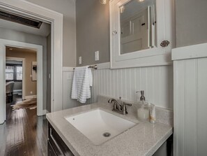 Une salle de bain avec un lavabo blanc, un miroir et une serviette accrochée au mur.