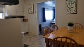 A compact kitchen with white cabinets, a dining table with chairs, and a potted plant. - House on the Camas Prairie - Located in Town (Grangeville)