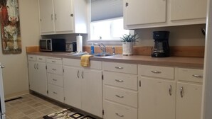 A kitchen with white cabinets, a microwave, a coffee maker, and a sink. - House on the Camas Prairie - Located in Town (Grangeville)
