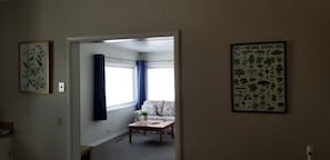 A room with a floral sofa, a small table with a plant, and a poster of Tanzanian trees.