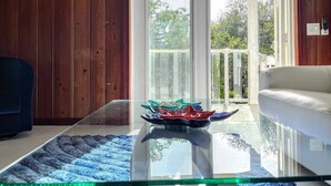 A modern living room with a glass coffee table, a blue rug, and a white sofa. - New* Nature view #2/ 1 BED pool, walk to beach (Fort Myers Beach)