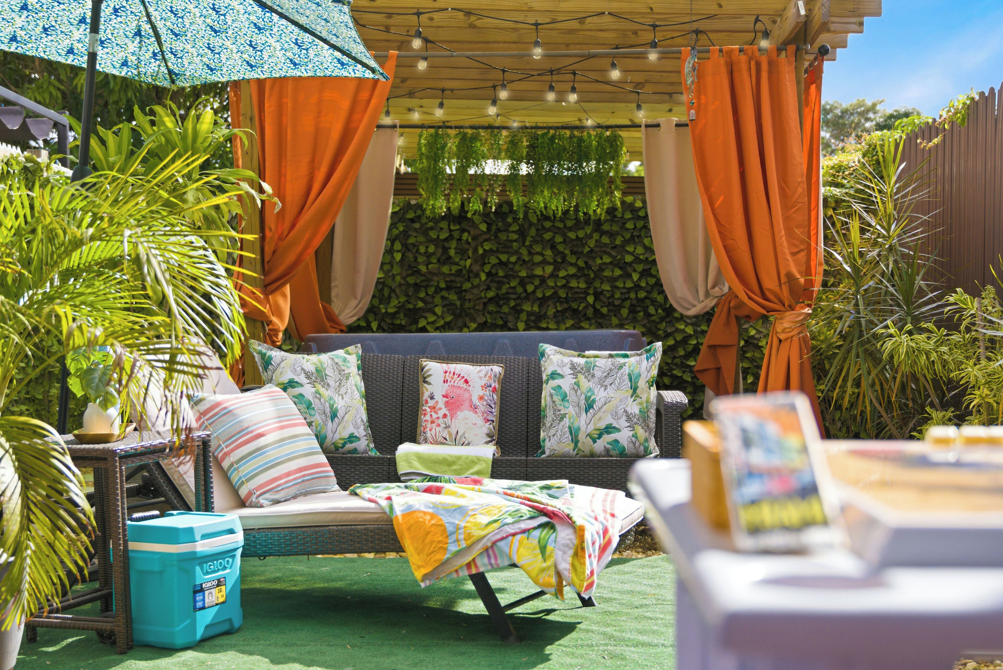 A cozy outdoor seating area with a cushioned sofa, a small table, and a colorful umbrella.