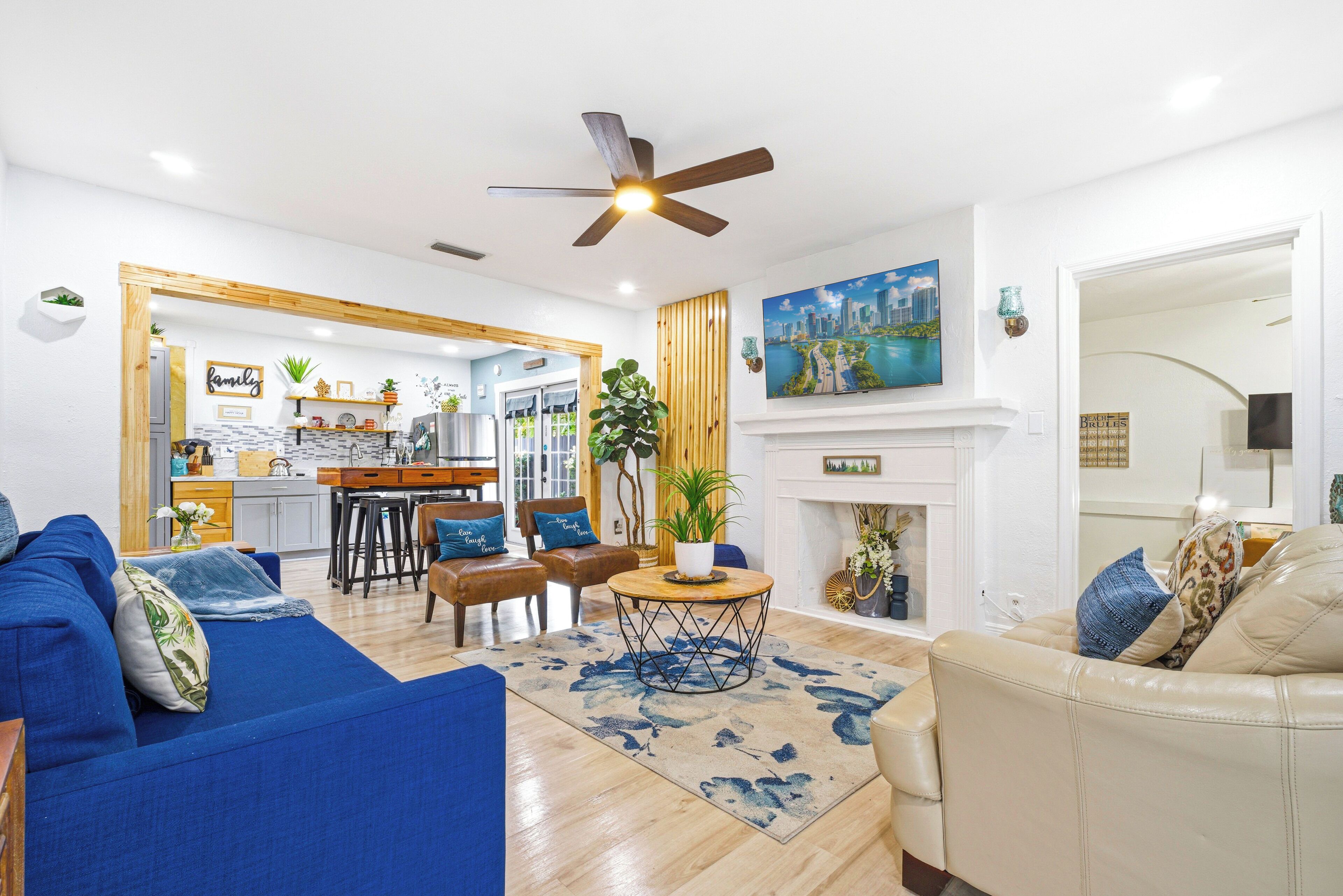 Una sala de estar moderna con un sofá azul, un sillón color crema y un comedor con mesa y sillas de madera.
