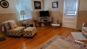 A living room with a sofa, ottoman, TV, and a patterned rug. - Make this house your HOME away from home (Meade)