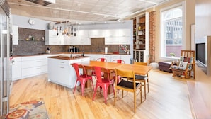 Una cocina moderna con armarios blancos, una mesa de comedor de madera y sillas rojas.