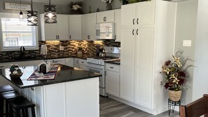Eine moderne Küche mit weißen Schränken, einer großen Kochinsel und einem Deckenventilator.