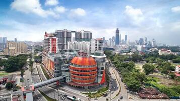 A modern building with a distinctive red and orange dome, surrounded by a busy urban area with multiple high-rise buildings and a clear sky.