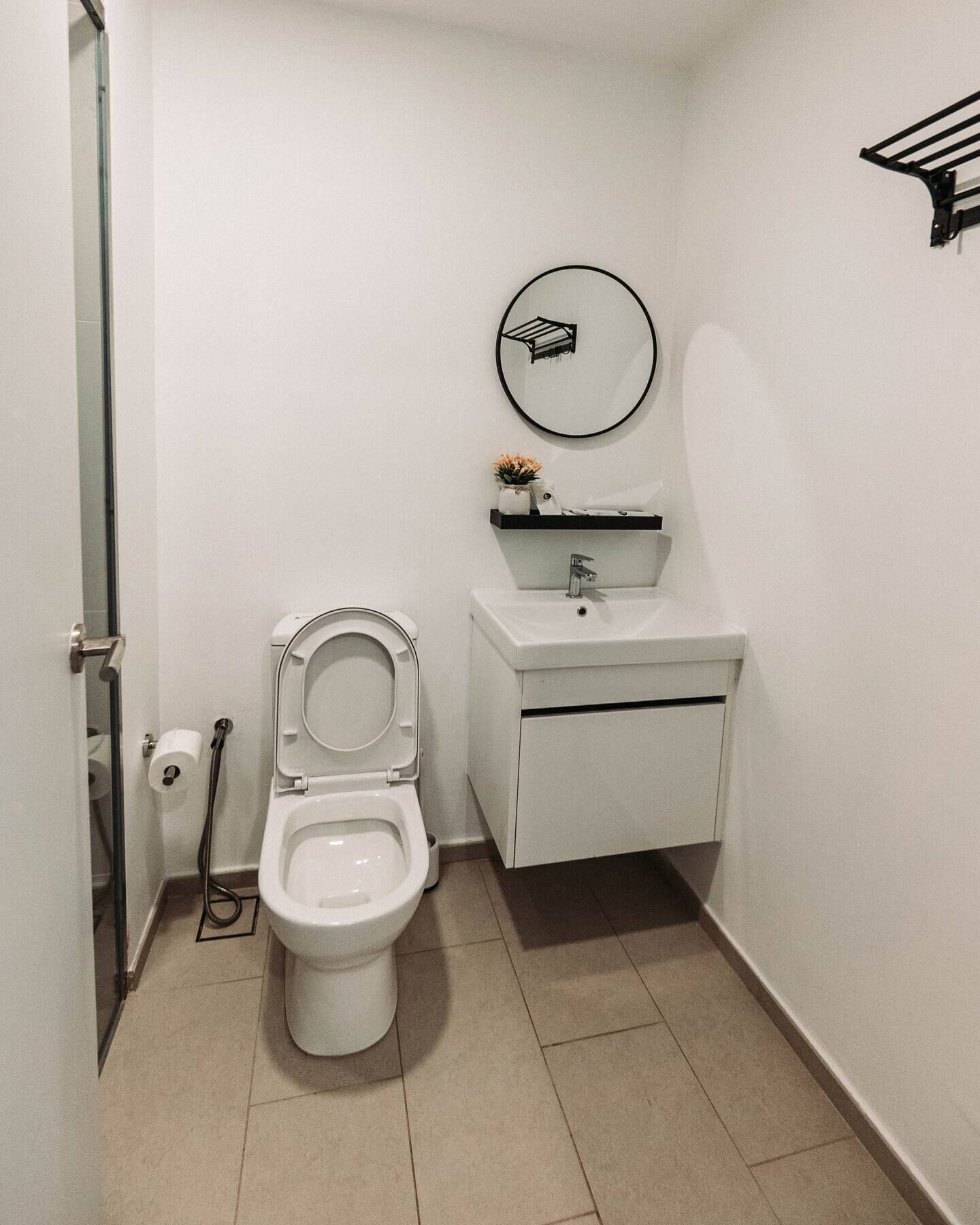 A small, clean bathroom with a toilet, sink, and mirror.