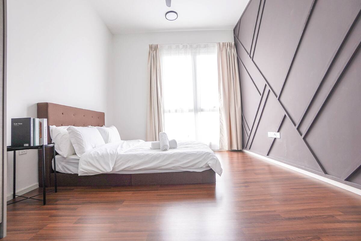 A modern bedroom with a bed, a bedside table, and a large window with curtains.