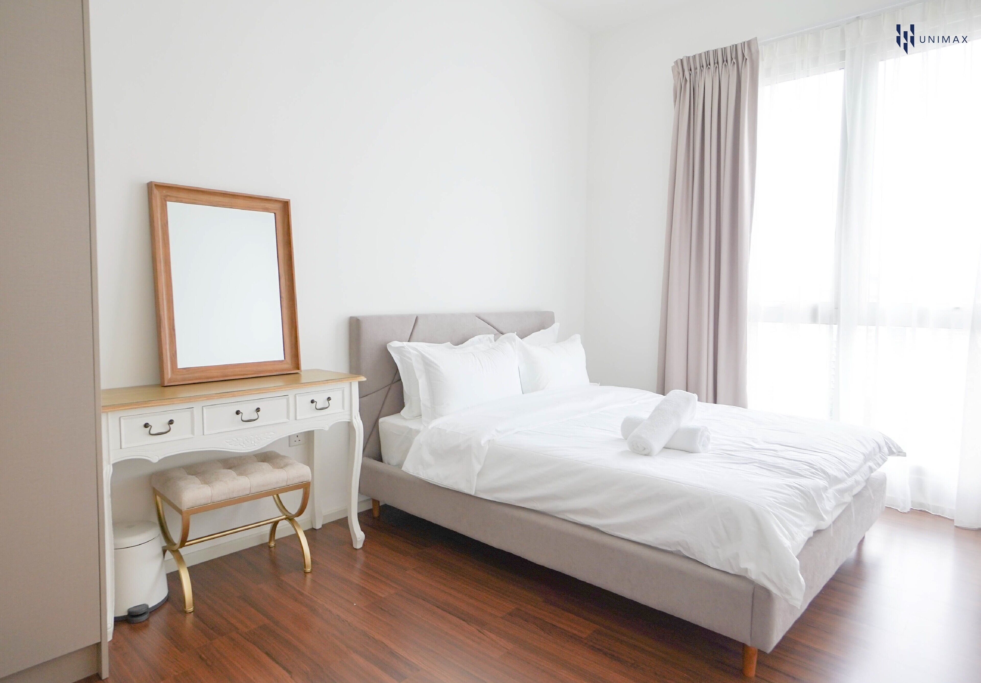 A bedroom with a bed, a bedside table, a mirror, and a bench.