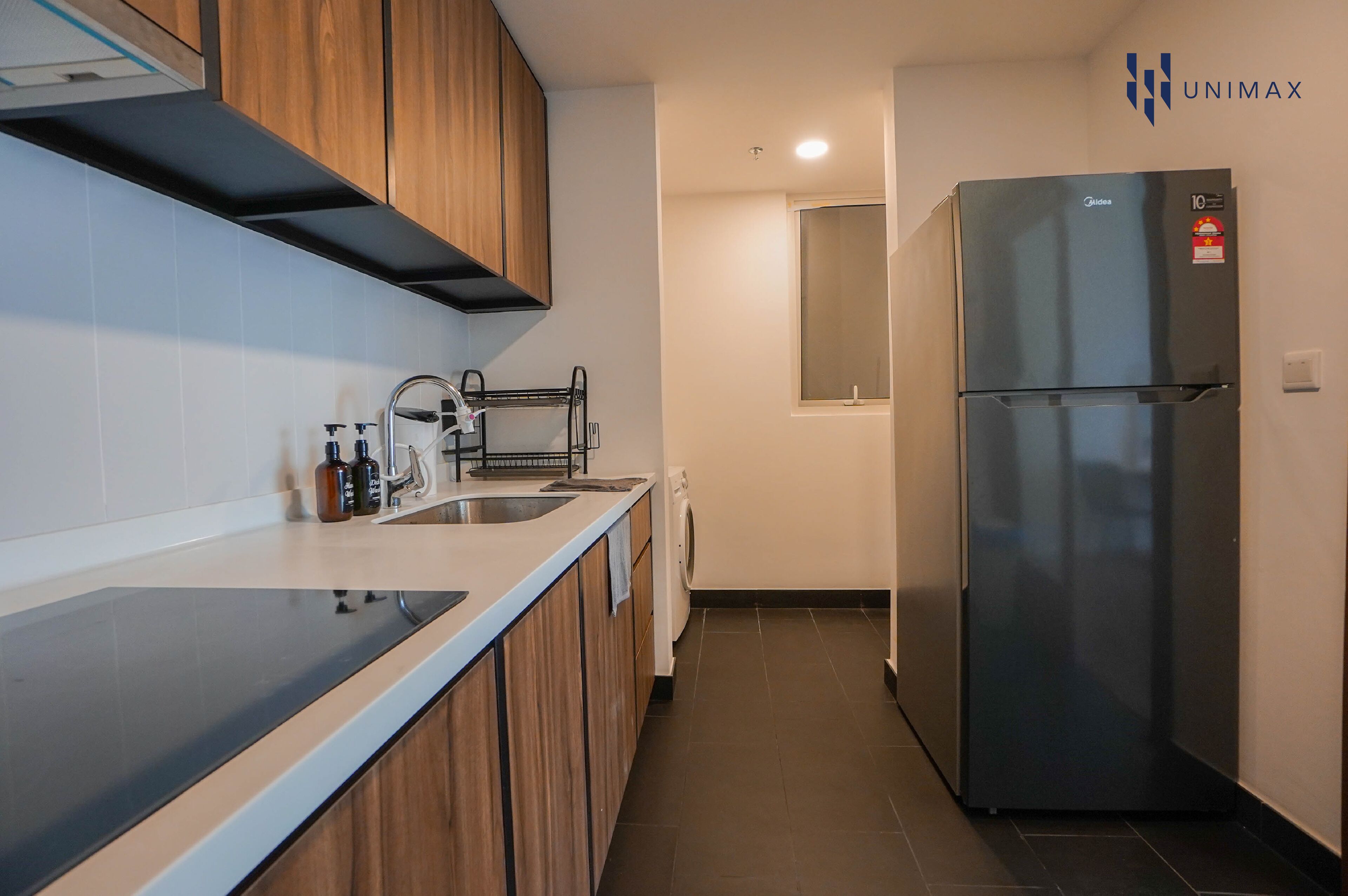 A modern kitchen with wooden cabinets, a stainless steel refrigerator, and a built-in oven.