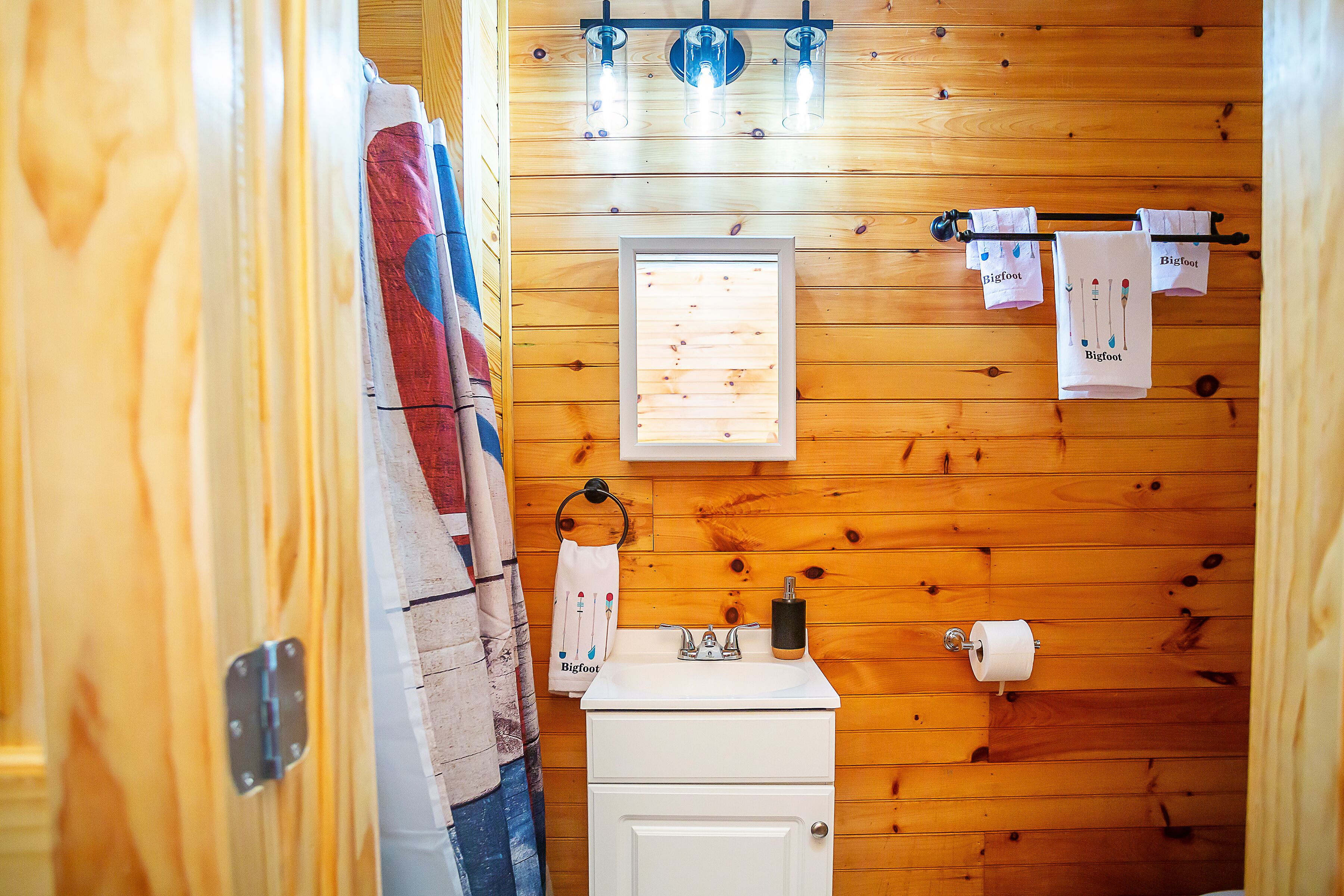 A wooden-paneled bathroom with a sink, towel rack, and a window.