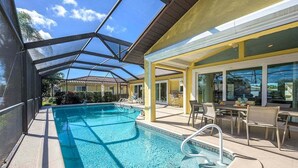 Ein Swimmingpool mit Glasdach, umgeben von Außenmöbeln und einer überdachten Terrasse.