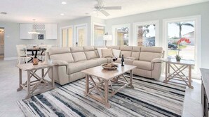 Ein modernes Wohnzimmer mit einem beige farbenen Ecksofa, zwei Holztischen und einem Streifen Teppich.
