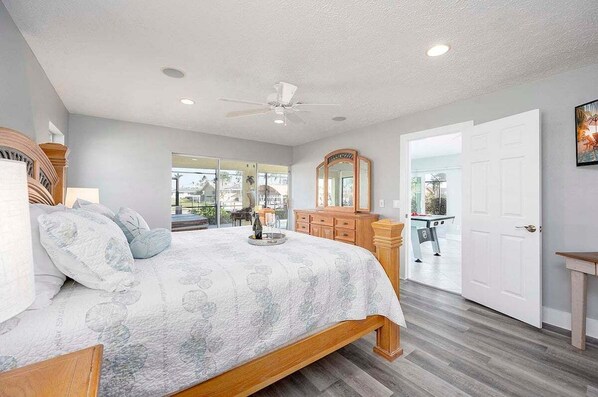 A bedroom with a bed, wooden headboard, a dresser, a mirror, and a ceiling fan.