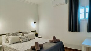 A neatly arranged bedroom with a bed, pillows, a bedside table, and a window with curtains. - Casa Dailos - 2 bedrooms with washing machine and wifi (Playa Del Ingles)