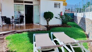 A patio area with a table and chairs, a small tree, and a white fence. - Casa Dailos - 2 bedrooms with washing machine and wifi (Playa Del Ingles)
