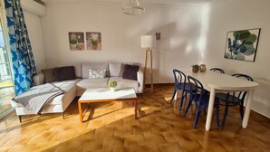 A living room with a sofa, coffee table, and dining area with chairs and a table. - Casa Dailos - 2 bedrooms with washing machine and wifi (Playa Del Ingles)