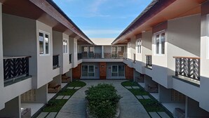 Un edificio moderno de varios pisos con un patio central, balcones y una pequeña zona ajardinada.