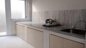 Una cocina moderna con un ventanal grande, un lavabo y una encimera con una tetera y vasos.