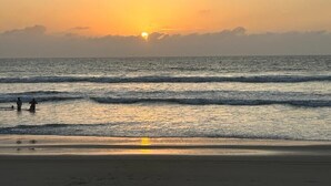 Une plage avec des vagues et un coucher de soleil.