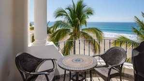A balcony with a view of the ocean, two wicker chairs, and a patterned table. - Mykonos Bay Resort at Zippers Surf Break (San José del Cabo)