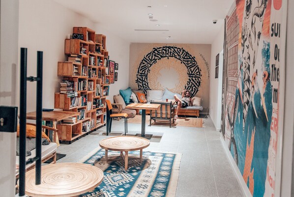 A cozy living room with a wooden bookshelf, a round coffee table, and a patterned rug.