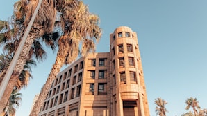 A tall building with a curved corner and multiple windows. - SEVEN Tel Aviv (Tel Aviv)