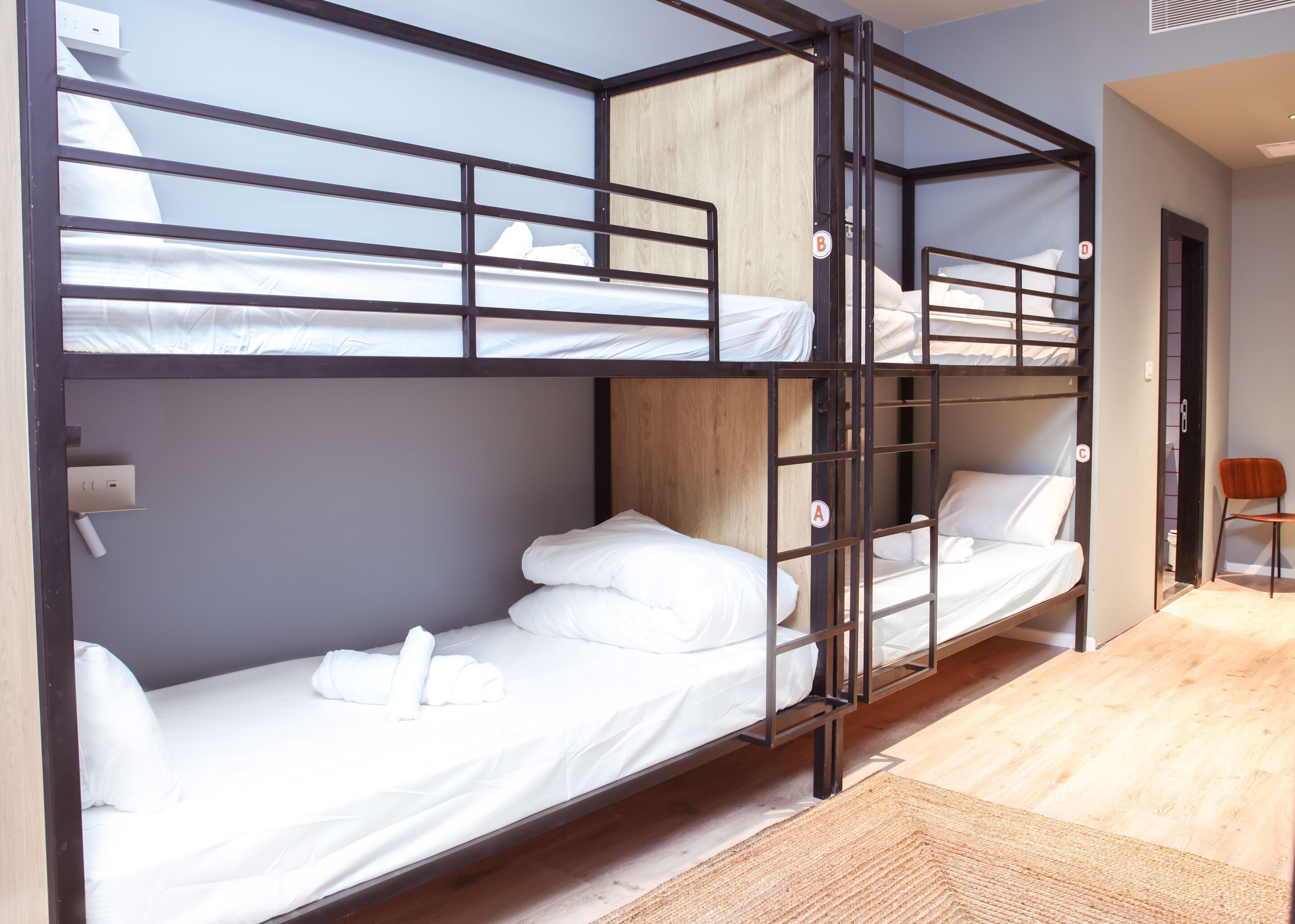 A bunk bed room with a wooden headboard, a small chair, and a door.