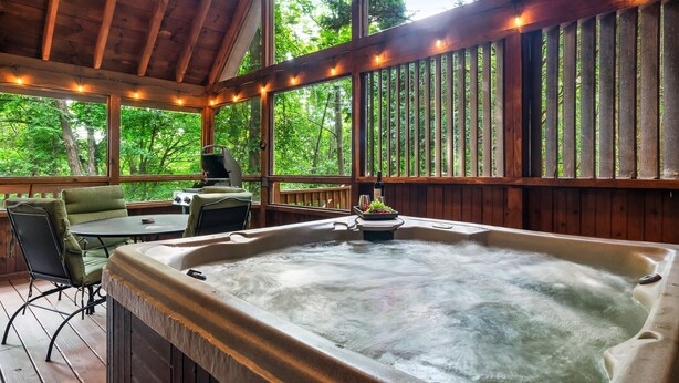 A hot tub with a view of a forest, a table with chairs, and a grill outside. - Hot Tub/Close2Downtown/Nearby Fishing Pond (Sevierville)