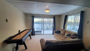 Uma sala de estar com mesa de bilhar, sofá e uma janela grande com vista para árvores.