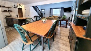 A modern kitchen with a wooden dining table, green chairs, and a built-in oven. - ZenNature with hottub & pet friendly (Tobyhanna)