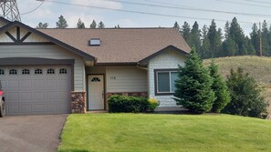 Welcome to a charming home with a garage and a front door marked 410A, set amidst a beautifully manicured lawn and lush evergreen trees.