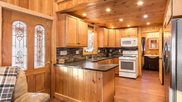 Una cocina amplia con armarios de madera, una isla central, microondas, horno y refrigerador.