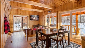 Un interior de madera con comedor, ventanas amplias y chimenea.