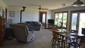 Una sala de estar con sofá, mesa de comedor con sillas, televisor y ventilador de techo.