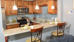 A kitchen with wooden cabinets, a stainless steel microwave, a gas stove, and a large island with bar stools.