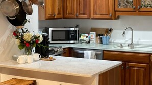 Une cuisine avec des meubles en bois, un four à micro-ondes, un évier et un plan de travail en marbre.