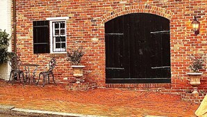 Un bâtiment en briques doté d’une grande entrée en arc de cercle, d’une petite fenêtre et d’une cheminée.