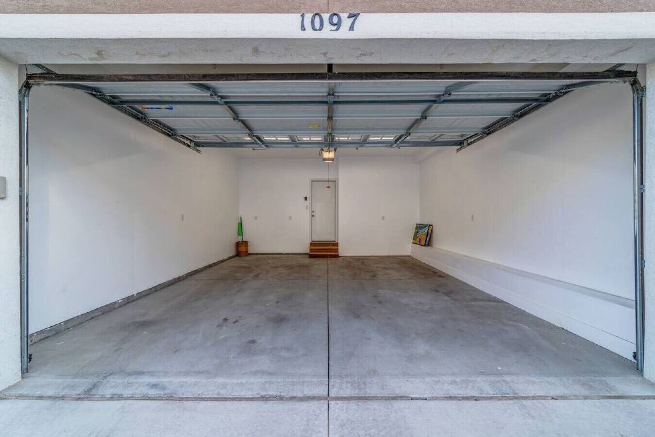 A clean, empty garage with a concrete floor and white walls.