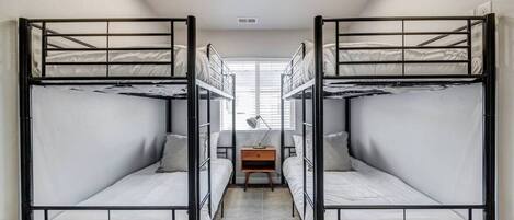 Ein Schlafsaalzimmer mit Etagenbetten, einem Schreibtisch und einer Lampe.