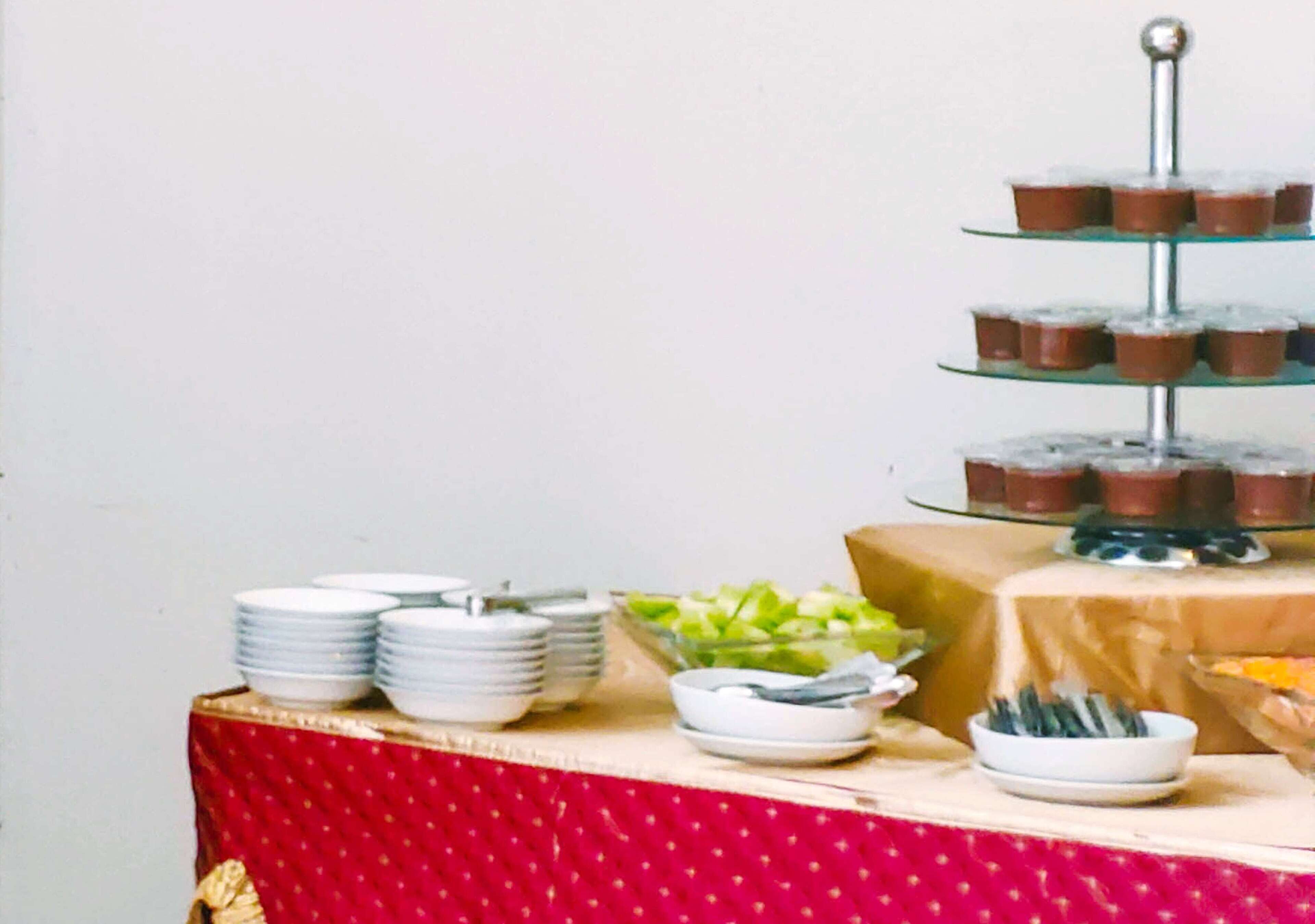 A buffet table with plates, bowls, and a tiered dessert stand.