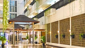 A spacious atrium with a wooden floor, hanging plants, and a covered seating area.
