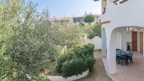 A courtyard with a dining area, surrounded by olive trees and a white building with a tiled roof. - Rubinia by Interhome (Valledoria)