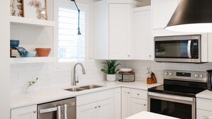 A modern kitchen with white cabinetry, a built-in microwave, a stove, and a sink.