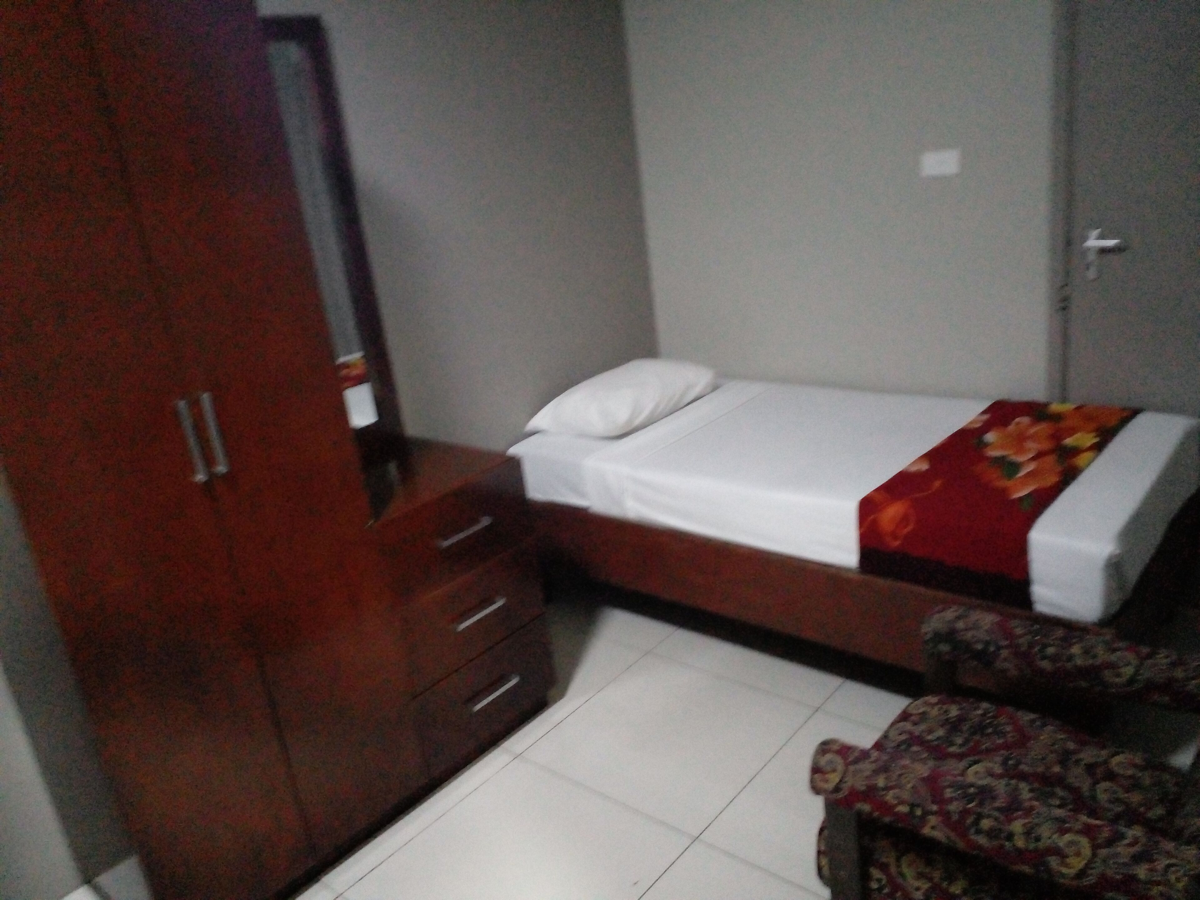 A bedroom with a bed, a wardrobe, and a chair.