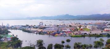 Zona costera industrial con almacenes, contenedores de envío y una gran masa de agua.
