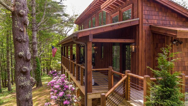 A wooden cabin with a deck, surrounded by trees and a flag. - Hawks Ridge - Eagles Nest home with fireplace, amenities (Banner Elk)